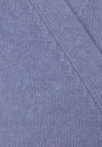 Gebreide omslag in licht lavendel, met een zachte textuur, een diagonale naad en gelijkmatige stiksels. Geen aanvullende patronen of accenten.