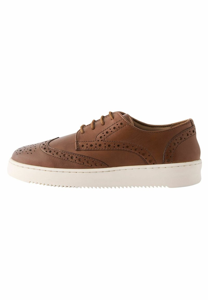 Hnědé kožené tenisky s brogue detaily, bílé gumové podrážky a kulatým designem špičky. Mají ploché tkaničky a hladký texturovaný povrch.