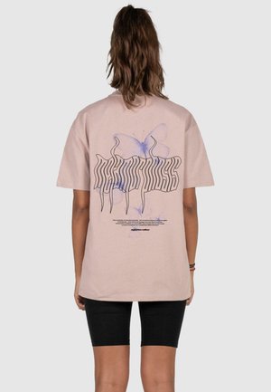 Lys rosa bomulds t-shirt med et grafisk design af en blå sommerfugl og stiliseret tekst på ryggen. Korte ærmer og afslappet pasform.