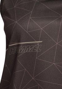 Tissu texturé foncé avec des motifs de lignes géométriques claires et le logo "HUMMEL" imprimé sur toute la surface.