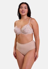 Soutien-gorge en dentelle beige clair avec un motif floral et des bonnets souples, associé à une culotte taille haute de couleur chair avec une texture lisse et une ceinture élastique.
