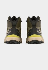 Ζευγάρι πεζοπορικών μπότες Salomon σε ελιάς πράσινο και μαύρο με μπεζ μεσαίες σόλες, εμφανιζόμενες από πίσω σε λευκό φόντο.