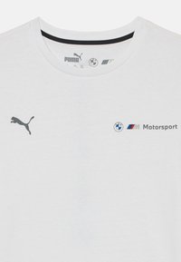 Balta marškinėliai iš medvilnės, su juodu Puma logotipu kairėje ir BMW Motorsport ženklu pilkos bei mėlynos spalvos centre.