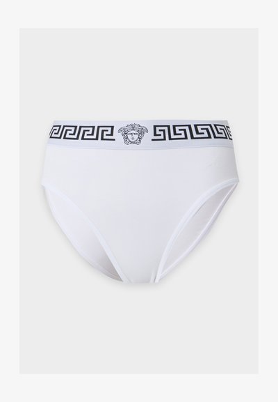 Culotte de bikini blanche avec un motif clé grecque noir et un logo tête de Méduse sur la ceinture, sur un fond uni.
