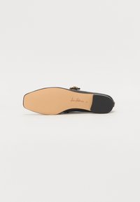 Talpă de pantof negru cu un design plat, realizată dintr-un material de cauciuc bej, textură netedă și detalii cu logo embossat.