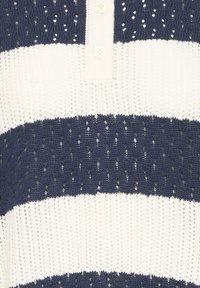 Mikina s námorníckymi a bielymi pruhmi, s výstrihom na gombíky, textúrovanou tkaninou a otvorenými pleteninovými vzormi pozdĺž pruhov.