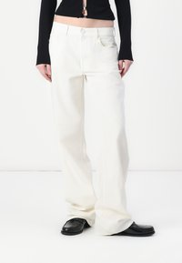 Pantaloni a gamba larga in denim bianco con vita alta, dotati di chiusura a bottone e due tasche frontali. Tessuto liscio e vestibilità comoda.