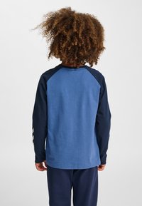 Långärmad tröja med blå kropp, marinblå ärmar och randiga detaljer. Tillverkad av mjukt material med avslappnad passform och rund halsringning.