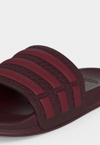 Μπορντό σανδάλι τύπου slip-on με υφασμένο πέλμα και τρεις ανυψωμένες οριζόντιες ρίγες στο πάνω λουράκι για στήριξη του ποδιού.
