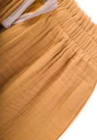 Puuvillased püksid sooja sinepikollase värviga, elastse vöökoha ja valge nööriga ning tekstuurse, kergest materiast.