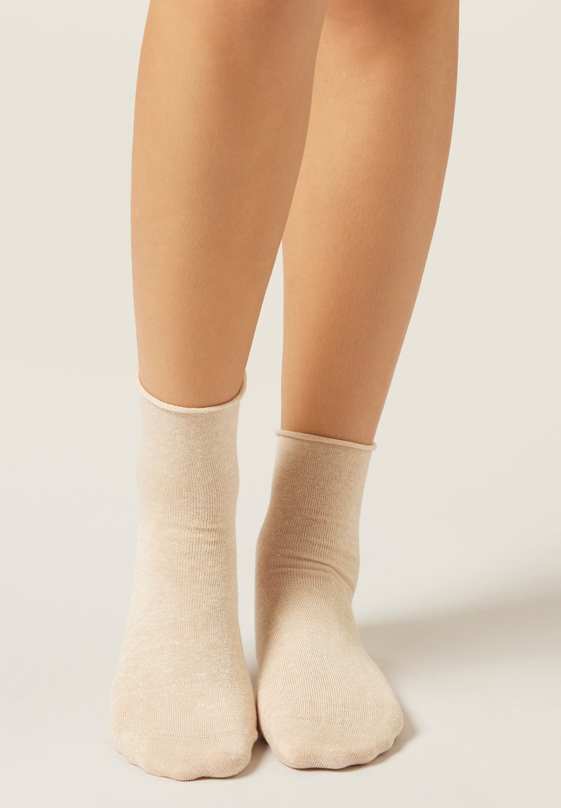Beige Knöchelsocken aus weichem, strukturiertem Stoff mit einem gerippten Bündchen, das sich eng um den Knöchel schmiegt, mit einer abgerundeten Zehenpartie.