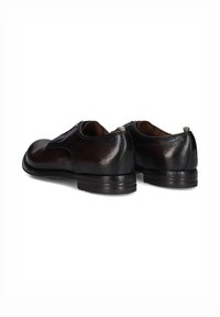 Zwarte leren schoenen met een gladde textuur, ronde neus en een lage gestapelde hak. Beschikt over een discreet ritsje en accentstiksel aan de achterkant.