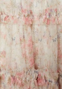 Genomskinligt blommigt tyg i pastellfärger med volangdetaljer och samlade veck. Har små blommönster i rosa, lila och grönt.