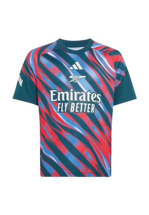 Dreng holder en rød Arsenal-fodbold, iført en Arsenal-trøje med Emirates Fly Better-logo og hvide shorts med røde kanter.