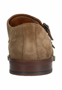 Chaussure en daim marron avec un bout arrondi et une semelle en bois. Elle présente un détail de boucle décoratif sur le côté. Texture lisse dans l'ensemble.