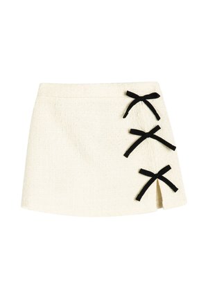 Minifalda blanca texturizada con tres lazos negros de cinta y una pequeña abertura frontal en el lado derecho.