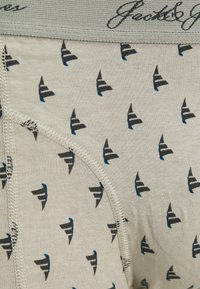 Helle graue Boxershorts mit einem subtilen Muster aus kleinen blauen und schwarzen Formen. Mit einem bequemen elastischen Bund. Aus weichem Baumwollmaterial.