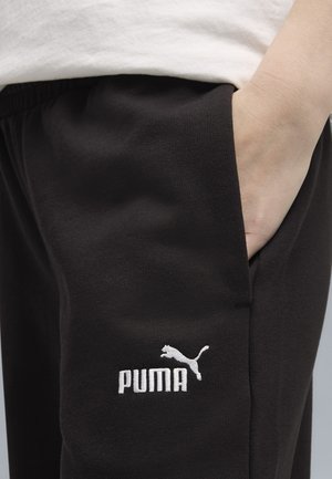 Black sweatpants made of soft fabric with an elastic waistband. Features a white embroidered Puma logo on the left side.