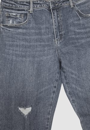Vaqueros de mezclilla gris con un pequeño agujero triangular rasgado en el muslo izquierdo, con bolsillos delanteros y cintura abotonada.
