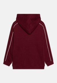 Felpa con cappuccio bordeaux dal finish testurizzato, con piping laterali bianchi e polsini e orlo a coste. Vista posteriore che mostra il collegamento del cappuccio.