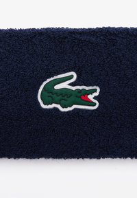 Ναυτική κεφαλοτύπου από φανέλα με λογότυπο πράσινου κροκοδείλου με κόκκινο στόμα, περιβεβλημένο από λευκές λεπτομέρειες. Μαλακή υφή, ορθογώνιο σχήμα.