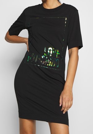 Černé tričkové šaty s volným střihem, krátkými rukávy a reflexním logem "LOVE MOSCHINO" ve středu. Hladká textura látky.