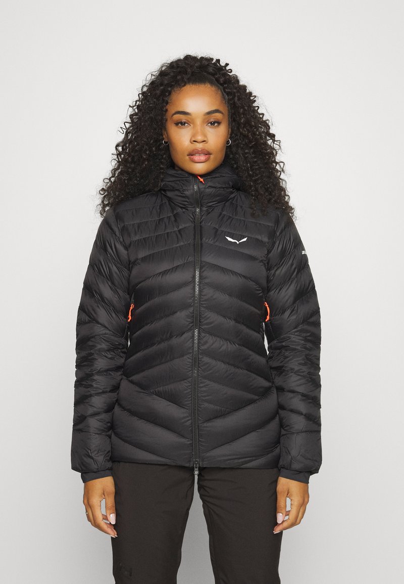 Black puffer jacket with chevron stitching, high collar, front zipper, and orange accents. Features elastic cuffs and a logo on the chest.
