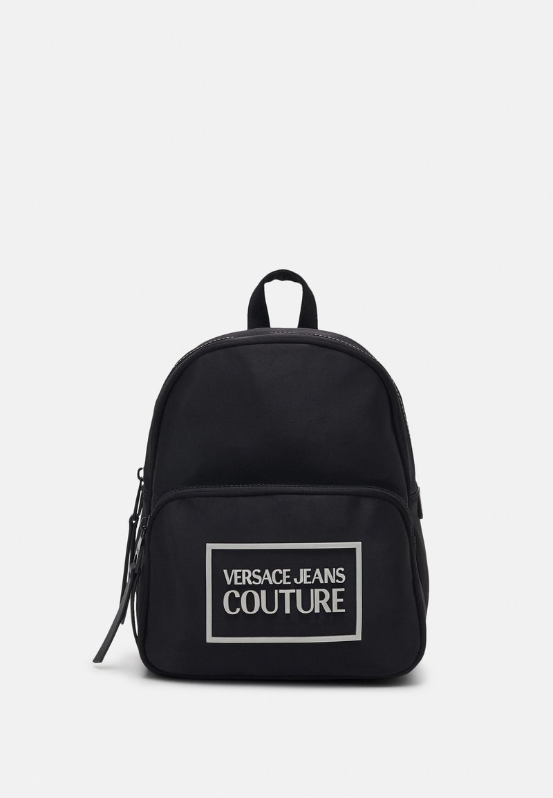 Svart nylonryggsäck med rundad form har en zippered framficka, handtag på toppen och en tydlig grafisk logotyp på framsidan.