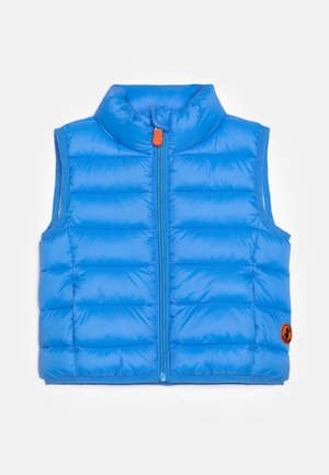 Niebieska pikowana kamizelka z poziomym przeszyciem, wysokim kołnierzem i pomarańczowym suwakiem. Z przodu po prawej stronie znajduje się okrągła naszywka z logo.