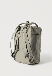 Harmaa kangasreppu säädettävillä remmeillä, etutaskulla ja tukevalla rakenteella. Kompakti muoto, jossa yläosa suljetaan. Mattapintainen ja yksinkertainen tyyli.