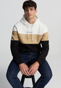 Felpa con cappuccio caratterizzata da tre fasce orizzontali di colore: bianco, beige e nero. Realizzata in misto cotone con cordini e testo ricamato.