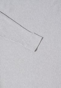 Szary sweter z prążkowanymi mankietami, o miękkiej teksturze i gładkiej powierzchni. Materiał wydaje się lekki i lekko elastyczny.