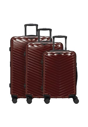 Trois valises rigides rouges avec des rainures diagonales, chacune avec quatre roues et des poignées télescopiques noires, disposées de la plus grande à la plus petite.