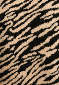 Gebreide stof met een zebra-patroon in zwart en zachte beige tinten, met een soepele textuur en vloeiende lijnen.