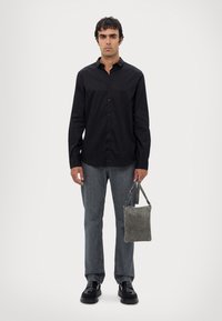 Zwarte lange mouwen knoopshirt, grijze straight-leg jeans, zwarte schoenen, met een kleine grijze tas met een bandje. Eenvoudig ontwerp en neutrale kleuren.