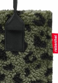 Texto rectangular con un patrón en verde olivo y negro. Presenta un lazo negro y una etiqueta de marca roja en el lado. Superficie suave y texturizada.