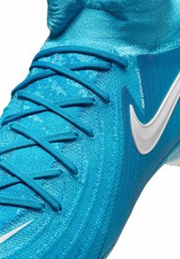 Helle blaue Nike Fußballschuhe aus strukturiertem Synthetikmaterial, mit einem sockenähnlichen Kragen, grauen Schnürsenkeln und einem weißen Swoosh-Logo.