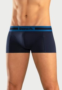 Temno modri bombažni bokserji z oprijetim krojem in širokim elastičnim pasom, ki ima kontrastno modro črto in logotip "Bench.".