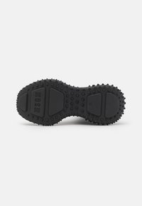 Suola di scarpa in gomma nera con un design testurizzato a punti, sezioni contornate e nome del marchio in rilievo. Forma piatta senza pattern di battistrada.