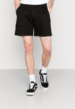 Zwarte katoenen shorts met een elastische tailleband, zijzakken en een rechte snit, gecombineerd met zwart-witte sneakers en witte crew-sokken.