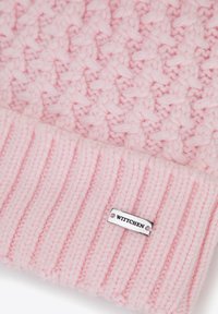 Cappello rosa lavorato a maglia con motivo testurizzato e bordo a coste. Include una piccola targhetta argentata con marchio "WITTCHEN".