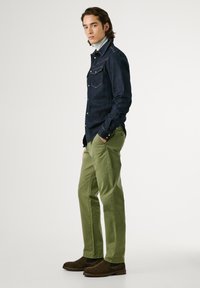 Denim shirt in dark blue with double chest pockets, paired with olive green chinos. Brown suede ankle boots with elastic sides.