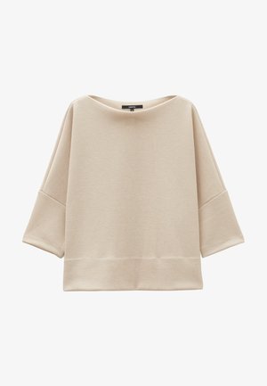 Beige oversized top gemaakt van ribbelstof. Kenmerkt een brede bateauhals en 3/4 mouwen. Rechte zoom met een ontspannen pasvorm.