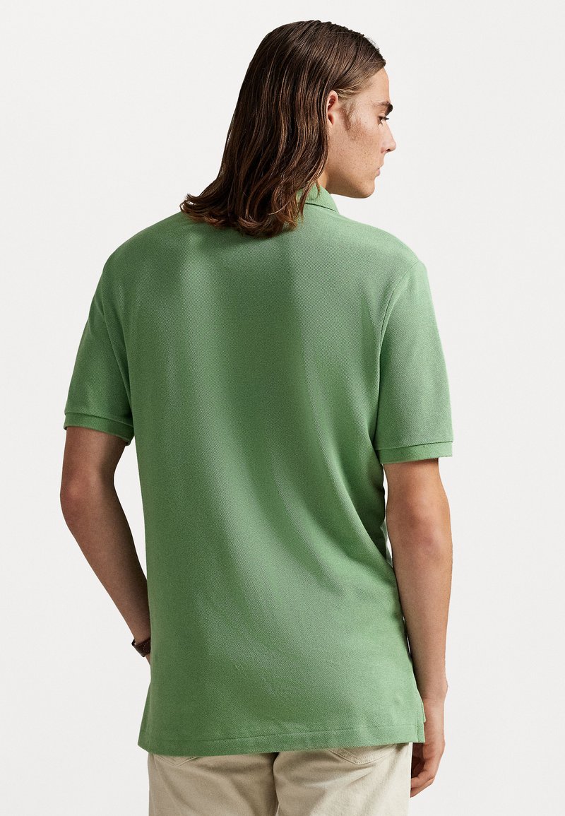 Polo shirt in lichtgroen, korte mouwen, met een gestructureerde stof en een klassieke kraag. Zijsplits aan de onderrand voor bewegingsgemak.