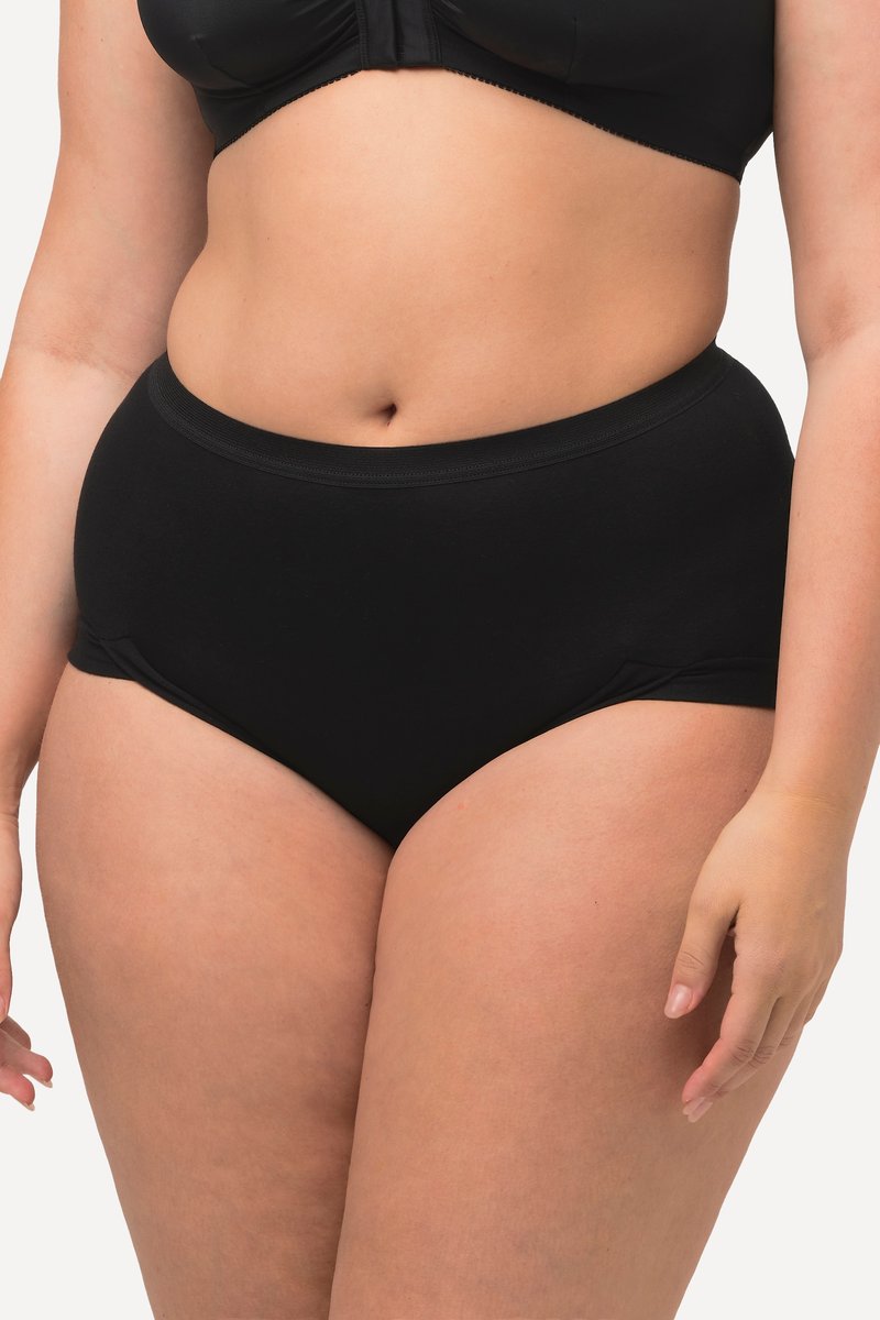 Donna che indossa biancheria intima nera a vita alta e un reggiseno nero, mostrata dal punto vita alle cosce su uno sfondo semplice.