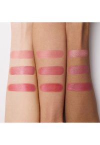 Trois bras présentant six échantillons de rouge à lèvres dans des nuances de rose variées, allant du mat au brillant, mettant en avant différents finis et couleurs.