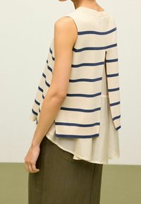Beżowy top bez rękawów w granatowe paski, z warstwowym designem i rozcięciem z tyłu, wykonany z lekkiego materiału.