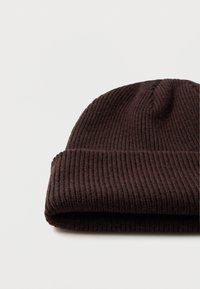 Gorro de punto acanalado marrón con puño doblado, hecho de un material suave y texturizado; presenta un diseño sin costuras con detalles de costura sutiles.