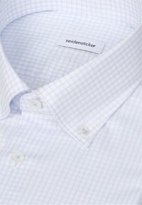Chemise blanche avec motif à carreaux bleu clair, col boutonné et étiquette de marque seidensticker visible à l’intérieur du col.