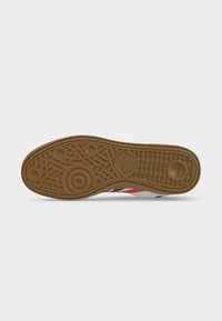 Επάνω μέρος καφέ παπουτσιού Adidas με υφή από κυκλικά σχέδια και το λογότυπο της Adidas ορατό κοντά στο κέντρο.